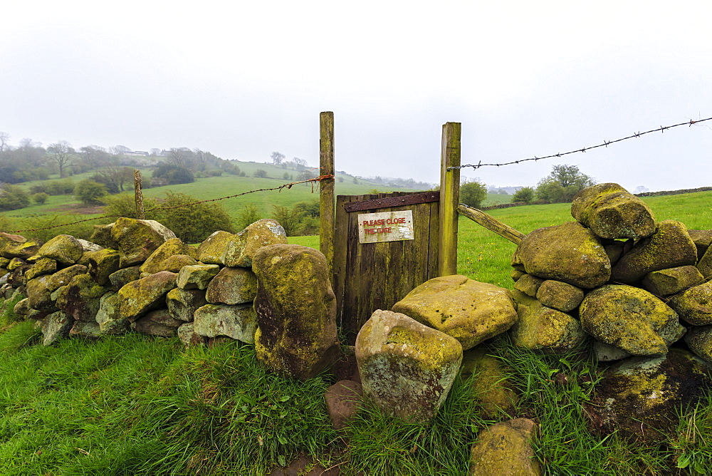 Footpath gate and dry stone wall near Elton on a murky spring day, Peak District National Park, Derbyshire, England, United Kingdom, Europe