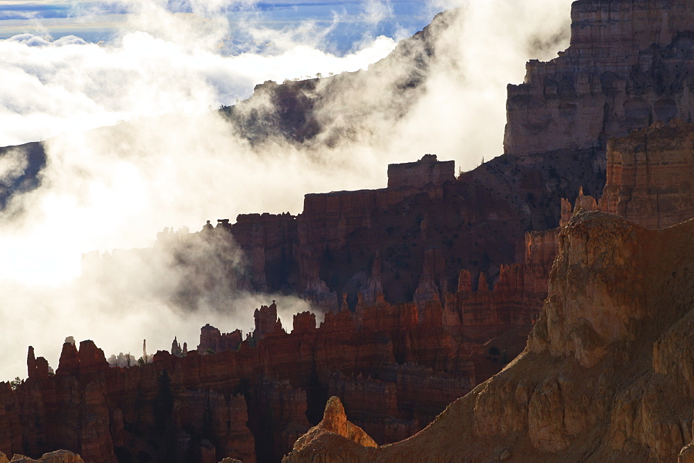 Backlit red ridges surrounded by the clouds of an early morning temperature inversion, Bryce Canyon National Park, Utah, United States of America, North America 