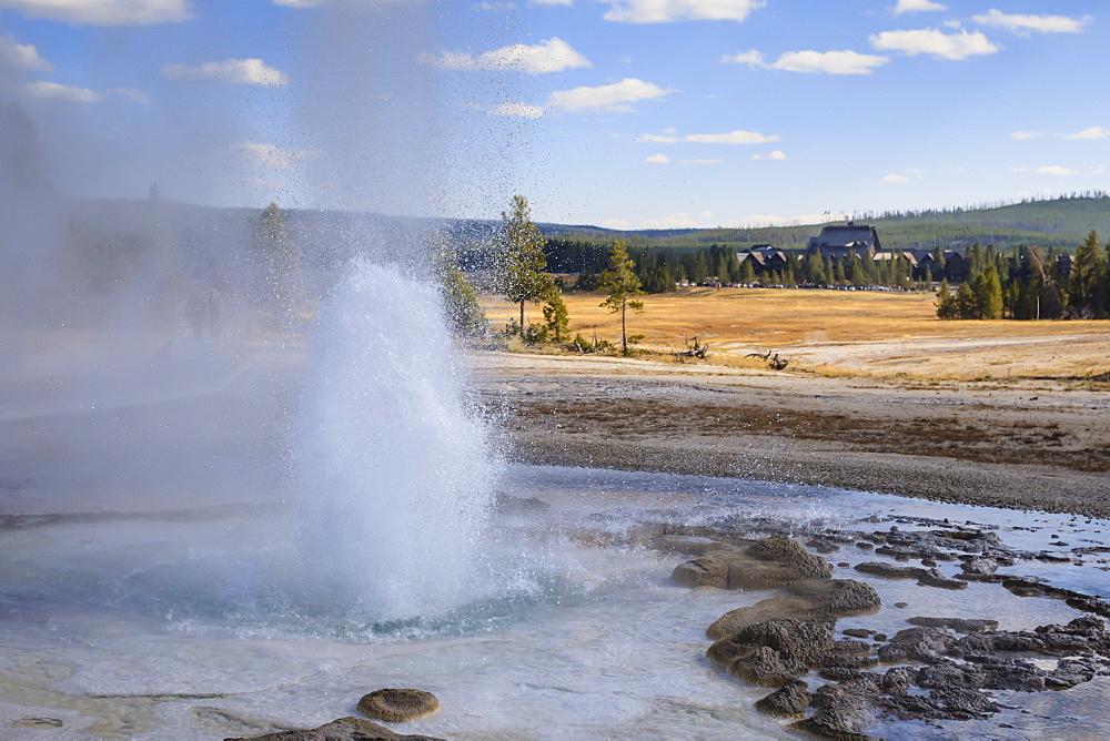 Erupting geyser and Old Faithful Inn, Upper Geyser Basin, Yellowstone National Park, UNESCO World Heritage Site, Wyoming, United States of America, North America