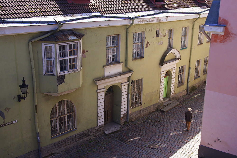 Man with hat in old street with pink and yellow coloured buildings, Tallinn, Estonia, Europe 