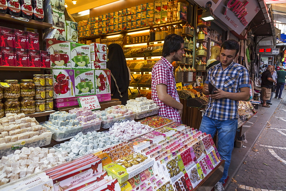 Sweet shop, man looks in wallet, busy street linking Grand and Spice Bazaarrs, Bazaar District, Istanbul, Turkey, Europe