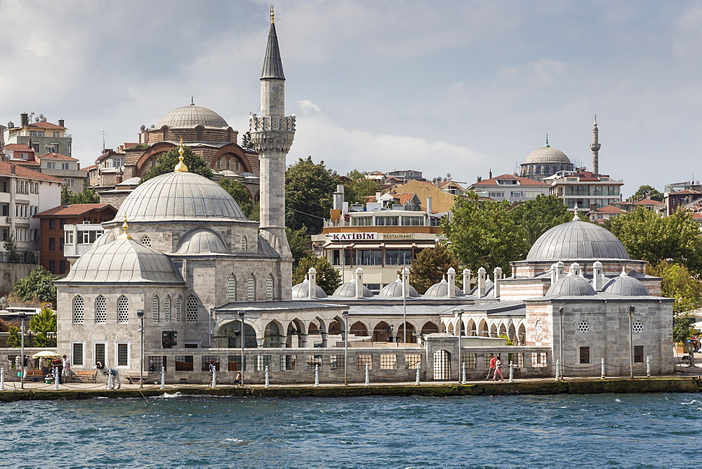 Couple walking past the Semsi Pasa Mosque, seen from the Bosphorus Strait, Uskudar, Istanbul, Turkey, Europe