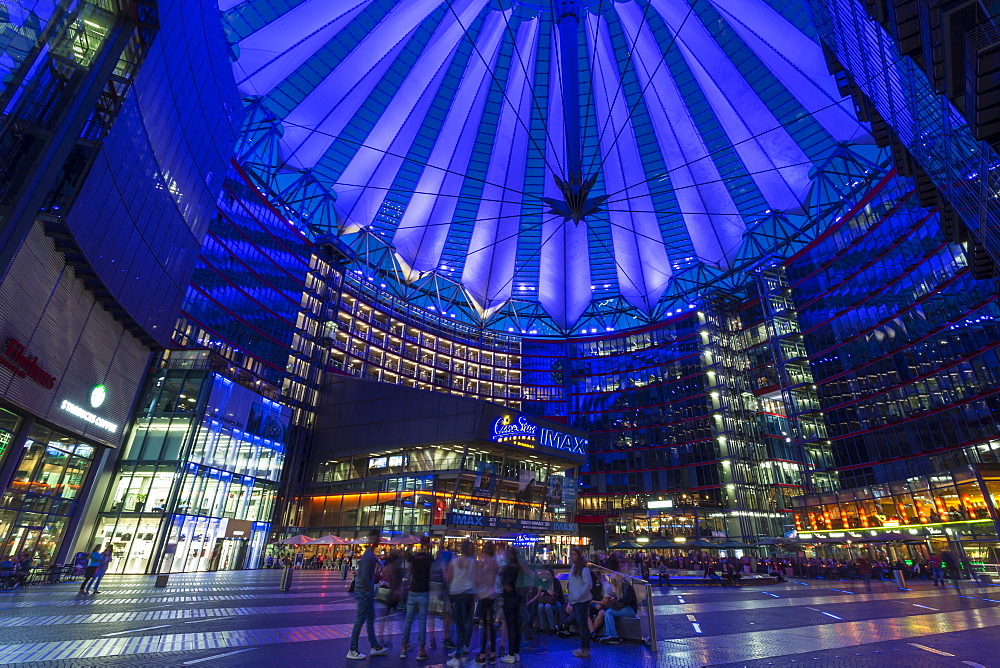 Young people relax and socialise in an illuminated Sony Center at night, Potsdamer Platz, Berlin, Germany, Europe