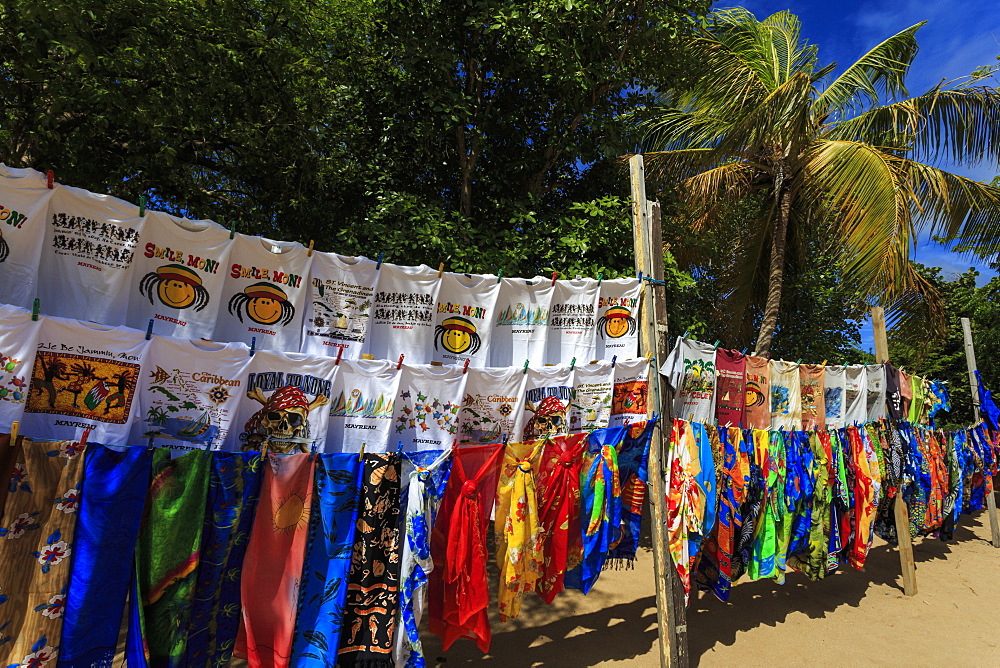 Colourful souvenir clothing on vendor stall with palm tree, beach, Saline Bay, Mayreau, Grenadines of St. Vincent, Windward Islands, West Indies, Caribbean, Central America