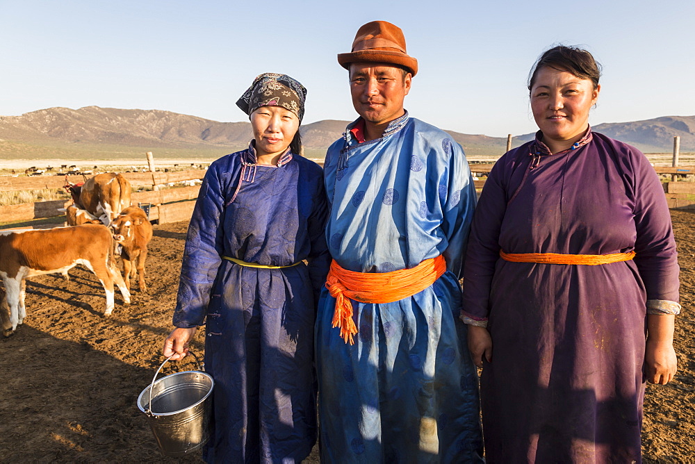 Smiling nomadic people in traditional clothes (deels) in milking pen at daw in summer, Nomad camp, Gurvanbulag, Bulgan, Mongolia, Central Asia, Asia