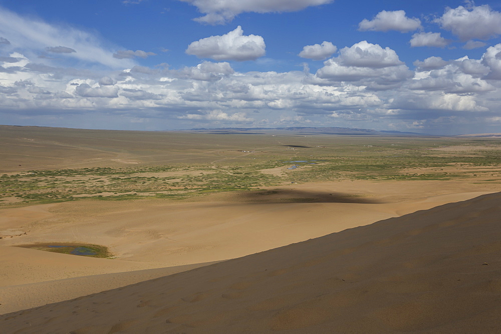 View down a huge sand dune towards a ger dotted plain and distant hills on a summer evening, Khongoryn Els, Gobi Desert, Mongolia, Central Asia, Asia