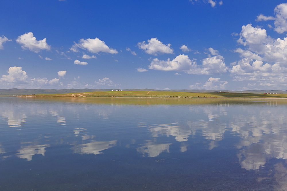 Fluffy clouds in a blue summer sky, reflected in a lake, distant reflected gers, Arkhangai, Central Mongolia,Central Asia, Asia