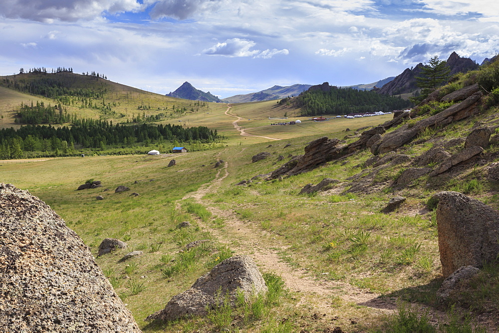 Path winds past hills and tourist ger camp towards distant mountains in summer, Terelj National Park, Central Mongolia, Mongolia, Central Asia, Asia