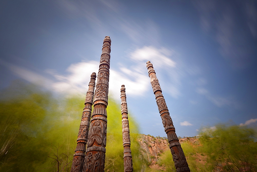 Naxi poles with wood carvings with moving clouds in a long exposure, Lijiang, Yunnan, China, Asia 