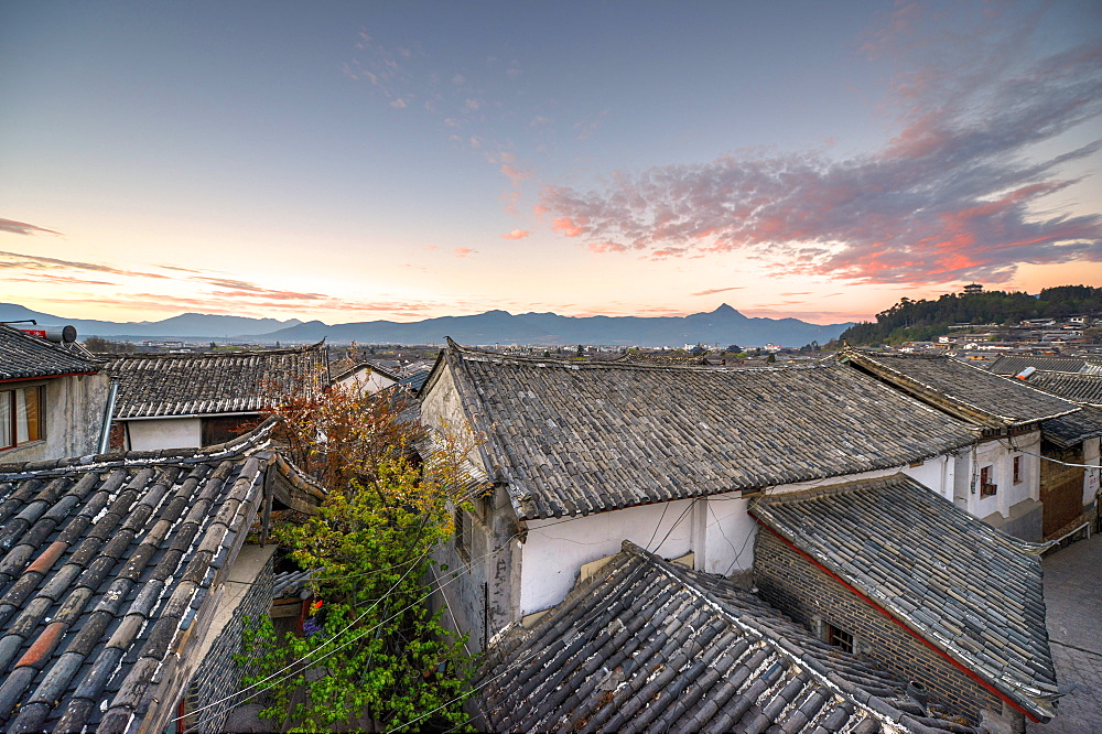 The sun is about to rise over the roofs and mountains of Lijiang Old Town, UNESCO World Heritage Site, Lijiang, Yunnan, China, Asia