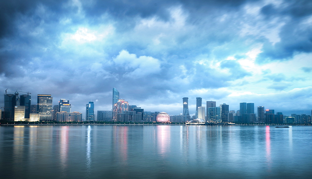 Blue hour shot of Jianggang district lights slowly coming to life under a dramatic sky, Hangzhou, Zhejiang, China, Asia