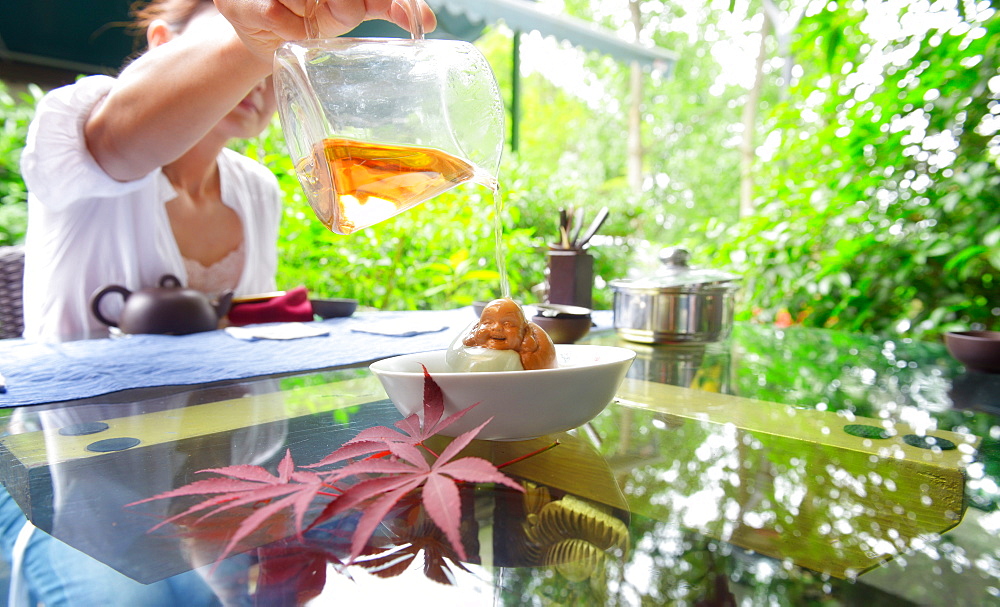 Dousing a small Buddha figurine with tea for good luck, Hangzhou, Zhejiang, China, Asia