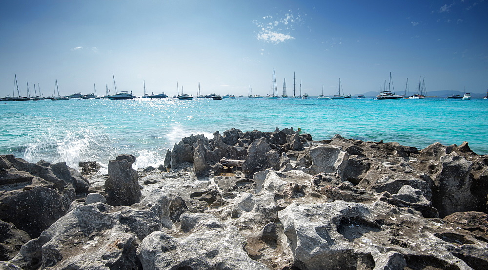 Jagged rocks with sailboats idling in the azure waters of Formentera, Balearic Islands, Spain, Mediterranean, Europe