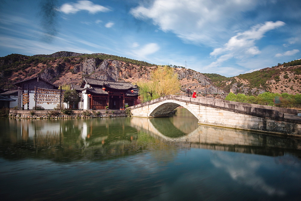 Guan Yin Gorge Park in a long exposure, with an actor in Monkey King costume sitting on the bridge, waiting for visitors, Lijiang, Yunnan, China, Asia 