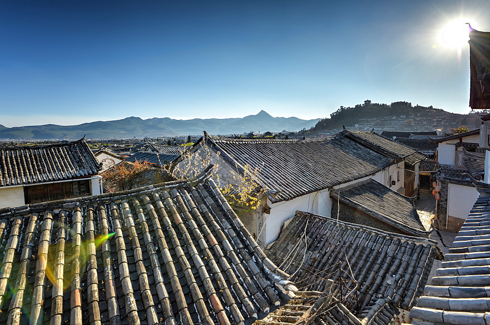 The roofs of Lijiang Old Town, UNESCO World Heritage Site, with Lion Hill silhouetted against a clear sky, Lijiang, Yunnan, China, Asia 