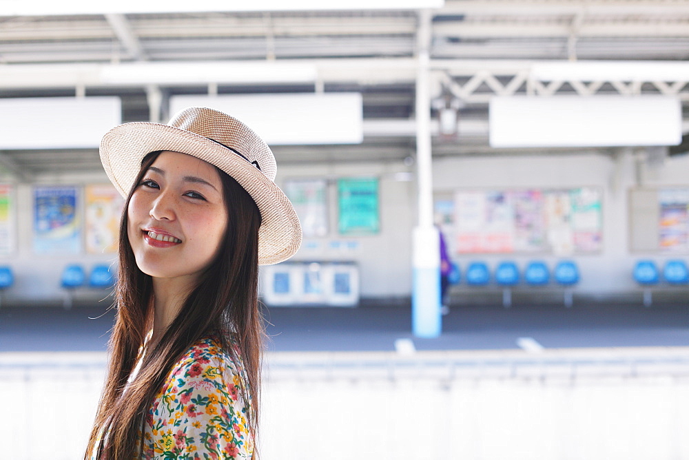 Portrait of a smiling Japanese woman with a hat at the station