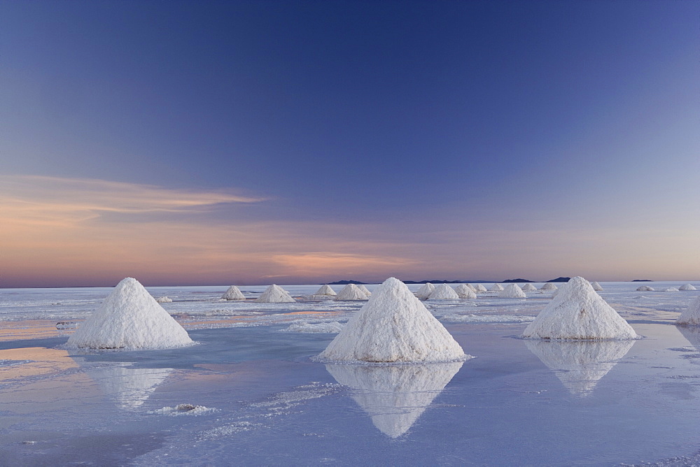 The salt pans of Salar de Uyuni, with shallow water and mineral deposits. White salt granules raked into heaps, Salar de Uyuni, Bolivia