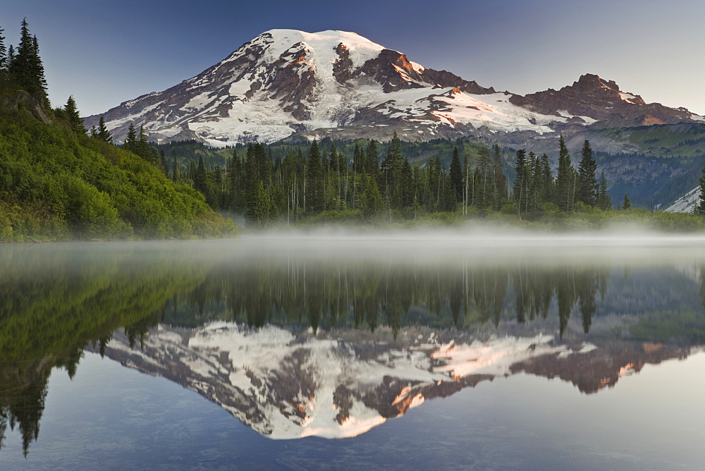 Mount Rainier, a snow capped peak, surrounded by forest reflected in one of many lakes in the Mount Rainier National Park, Mount Rainier National Park, Washington, USA