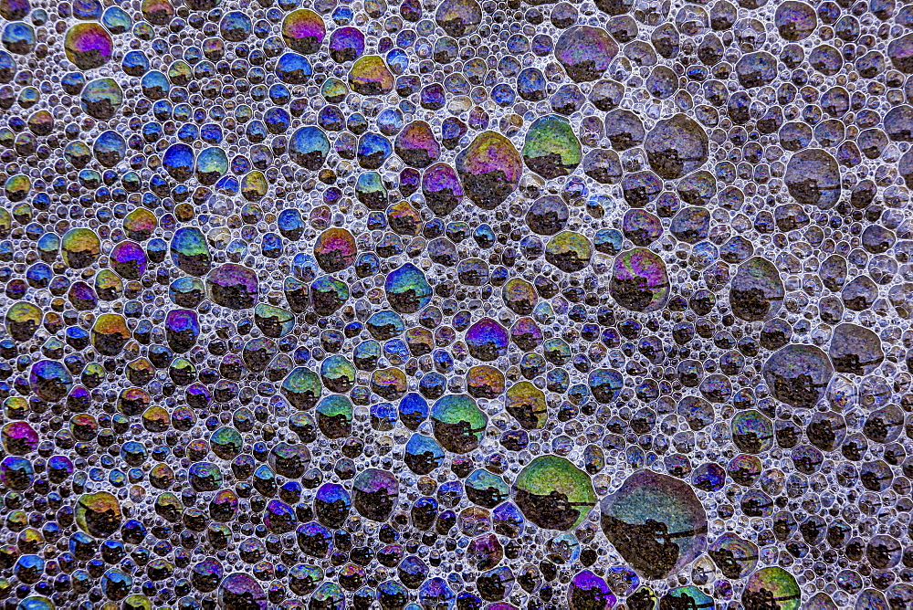 Froth and bubbles of air reflecting rainbow colours on the surface at Cannon Beach, Oregon, USAAstoria, Oregon, USA