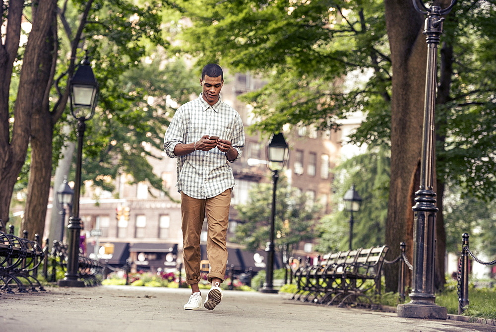 A man walking through a town square looking at his smart phone