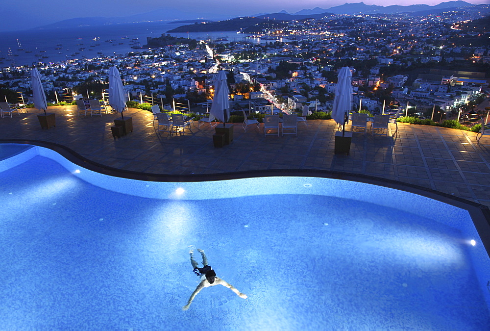 View of person swimming in pool of Hotel The Marmara Pool and cityscape in Bodrum, Turkey