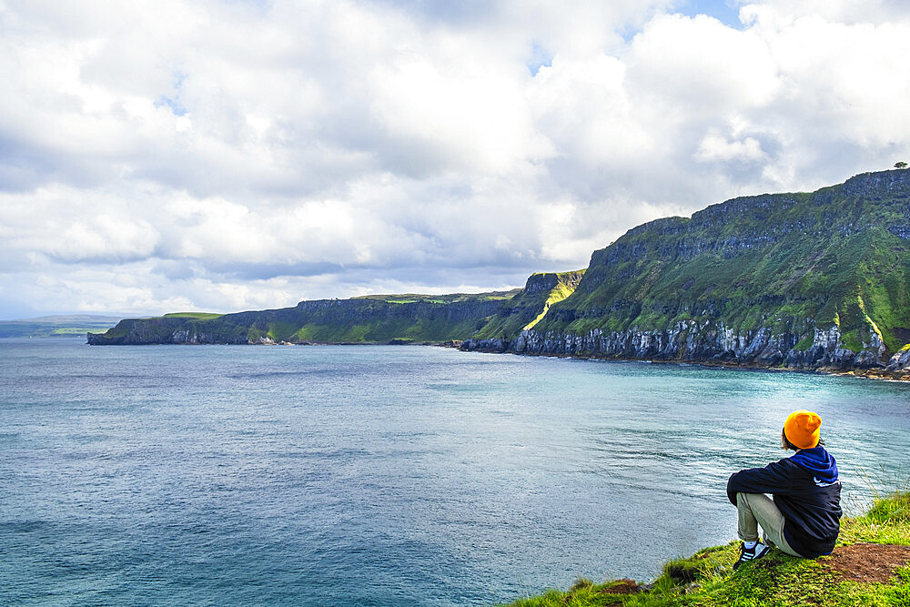 A young hiker taking a rest on a walking trail along the Antrim coast, Ulster, Northern Ireland, United Kingdom, Europe