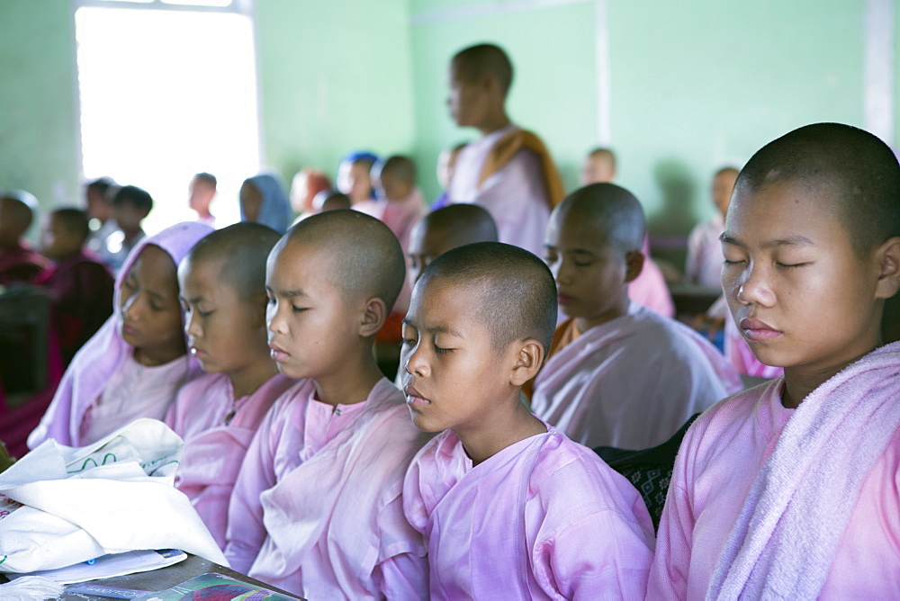 Buddhist novice schoolgirls conducting class meditation in the school classroom before lessons, Sagaing, Myanmar, Southeast Asia