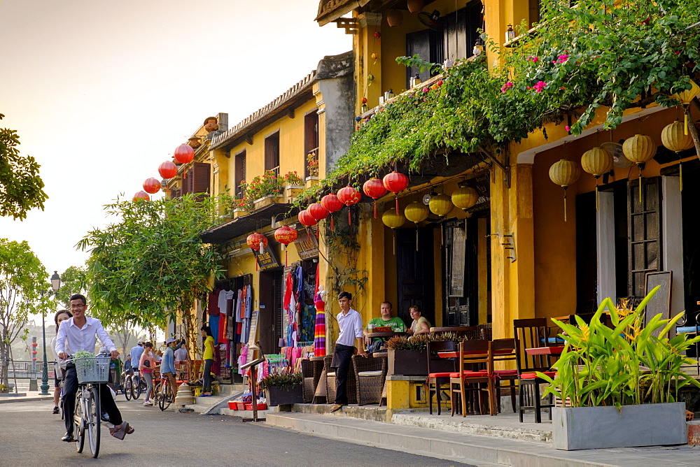 Young couple riding a bicycle past attractive cafe shop houses in Hoi An, Vietnam, Indochina, Southeast Asia, Asia