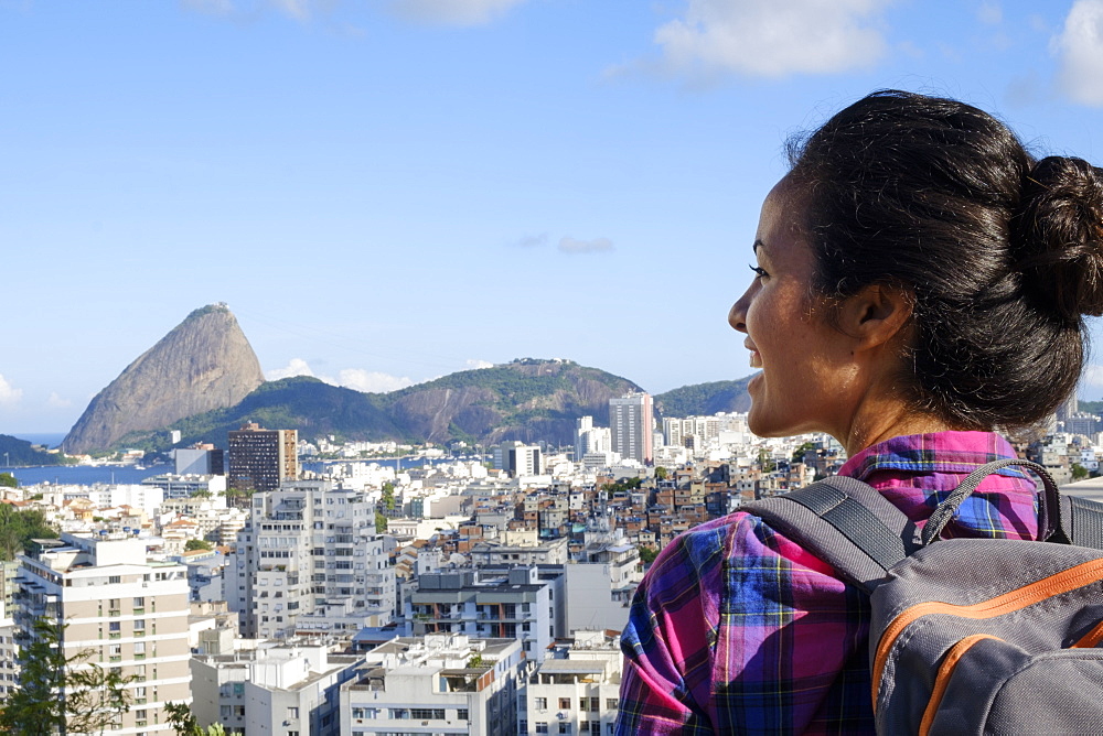 Young backpacker on her mobile phone in central Rio de Janeiro with the Sugar Loaf in the distance, Rio de Janeiro, Brazil, South America