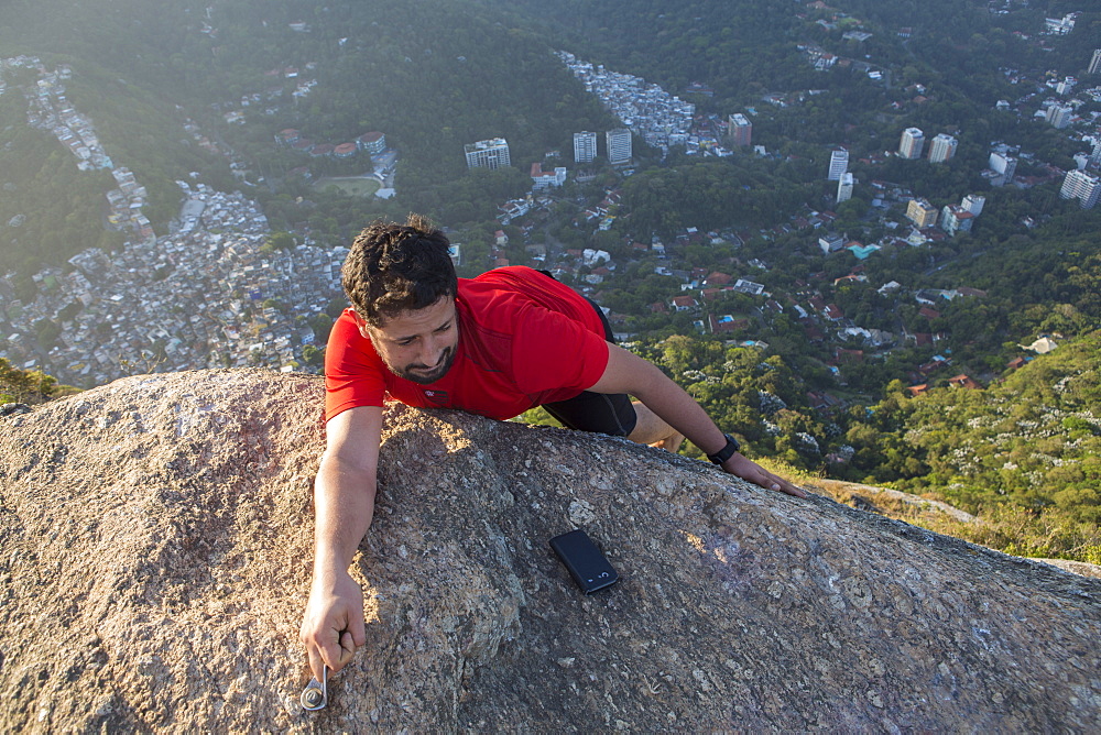 Climber on the top of the Morro dos Dois Irmaos (Two Brothers Hill) with Rocinha favela below, Rio de Janeiro, Brazil, South America