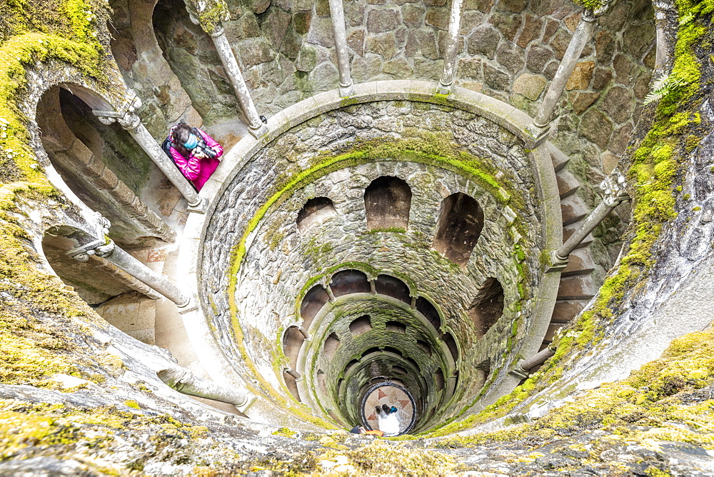 Photographer at the top of the spiral stairs inside the towers of Initiation Well at Quinta da Regaleira, Sintra, Portugal, Europe