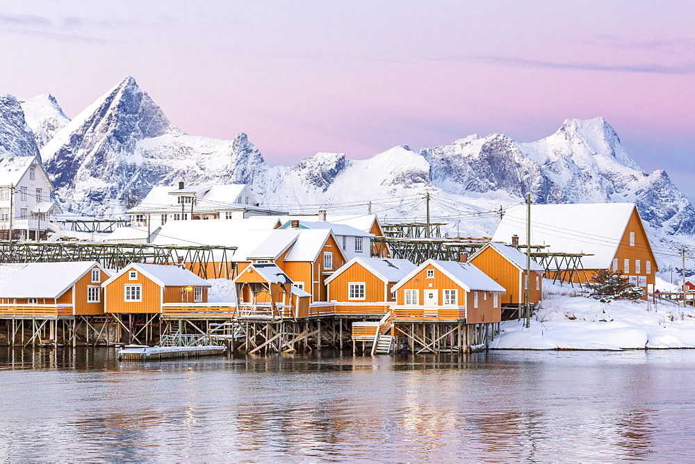 The colors of dawn frame the fishermen's houses surrounded by frozen sea, Sakrisoy, Reine, Nordland, Lofoten Islands, Arctic, Norway, Scandinavia, Europe