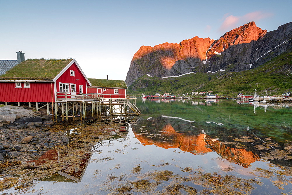 Fishing village and peaks reflected in water under midnight sun, Reine, Nordland county, Lofoten Islands, Arctic, Northern Norway, Scandinavia, Europe