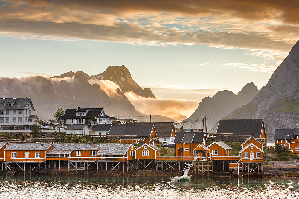 Sunset on the fishing village framed by rocky peaks and sea, Sakrisoya, Nordland county, Lofoten Islands, Arctic, Northern Norway, Scandinavia, Europe