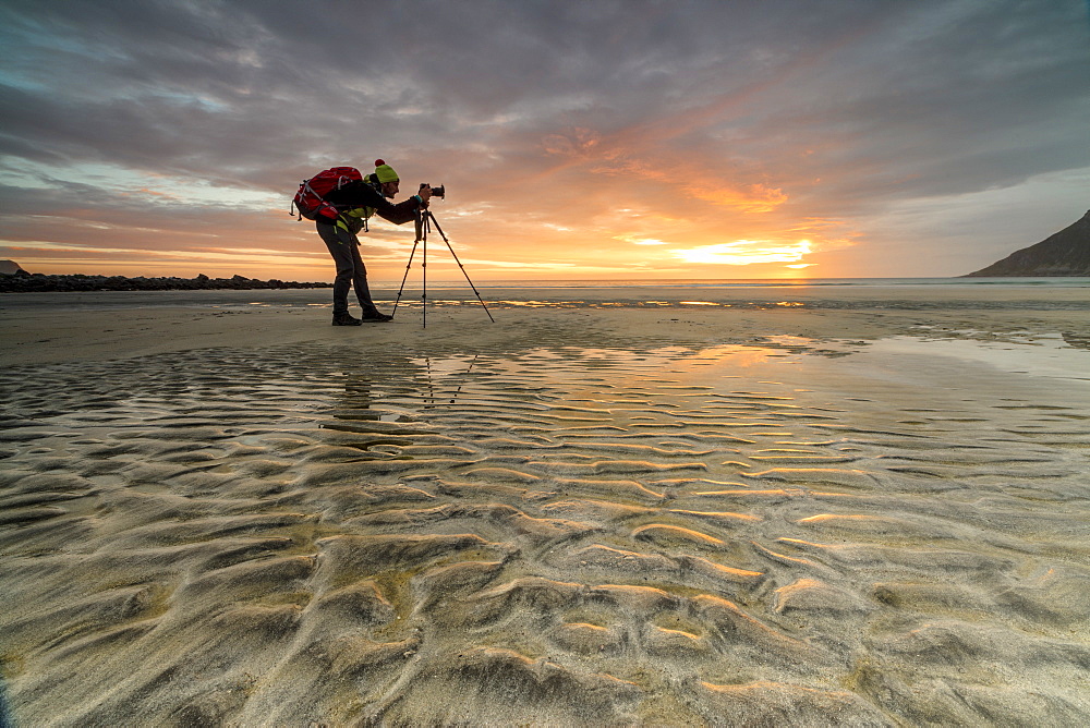 Midnight sun frames photographer in action on Skagsanden beach, Ramberg, Nordland county, Lofoten Islands, Arctic, Northern Norway, Scandinavia, Europe