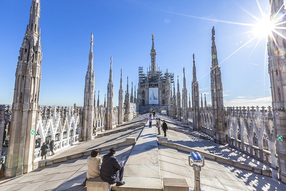 Tourists among the white marble spiers on the top of the Duomo, Milan, Lombardy, Italy, Europe