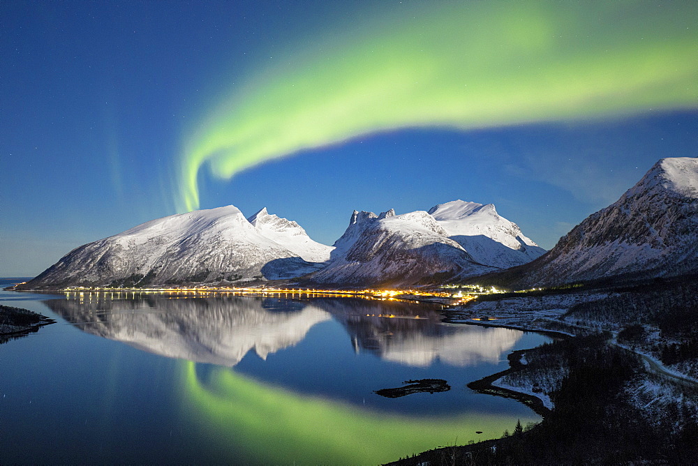 Northern lights (aurora borealis) and stars light up the snowy peaks reflected in the cold sea, Bergsbotn, Senja, Troms County, Norway, Scandinavia, Europe