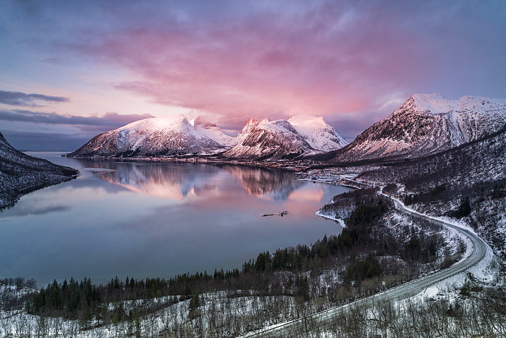 Pink sky and clouds on the snowy peaks reflected in cold sea at sunset, Bergsbotn, Senja, Troms County, Norway, Scandinavia, Europe