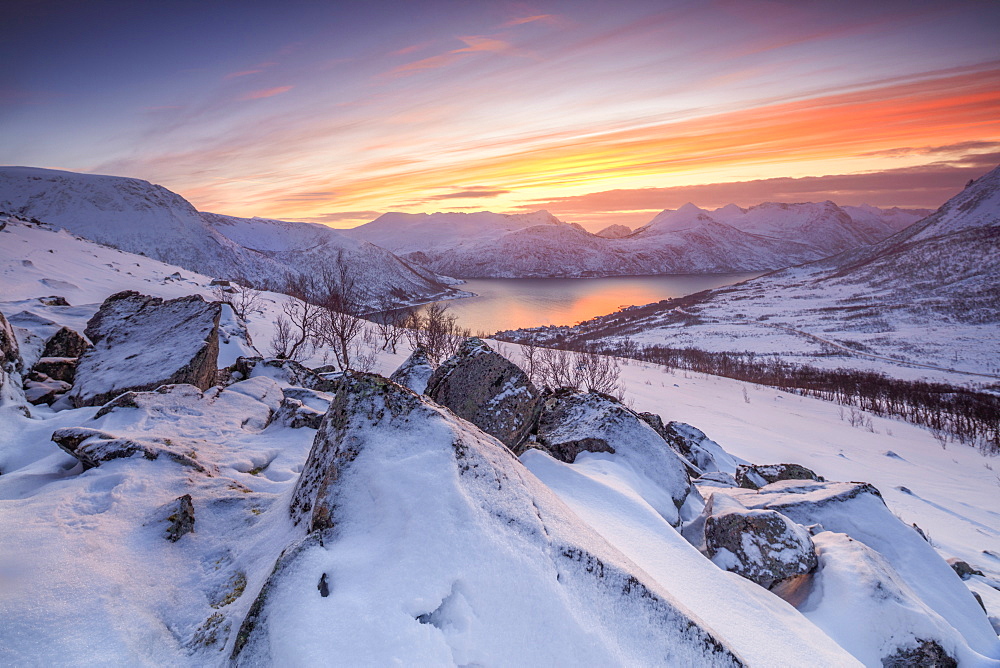 Frozen sea surrounded by snow framed by the orange sky at sunset, Torsken, Senja, Troms County, Arctic, Norway, Scandinavia, Europe