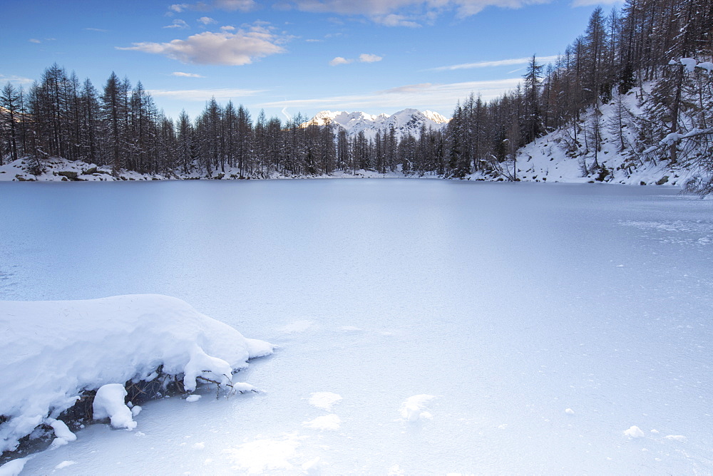 View of the frozen Lago Azzurro surrounded by snow at dawn, Spluga Valley, Province of Sondrio, Valtellina, Lombardy, Italy, Europe