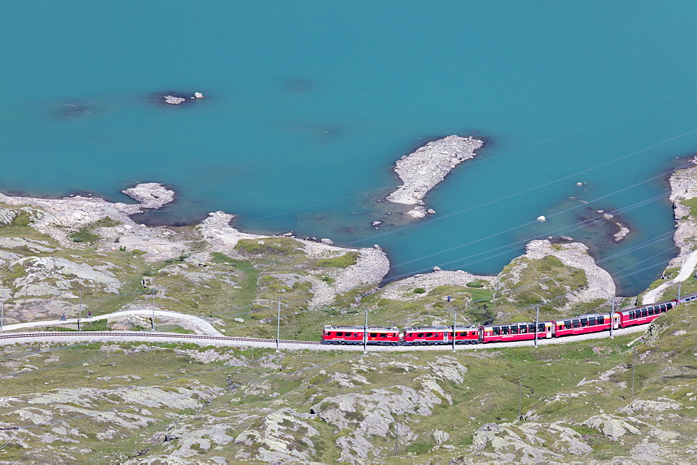 The Bernina Express train passes on the shores of Lago Bianco, Bernina Pass, Canton of Graubunden, Engadine, Switzerland, Europe