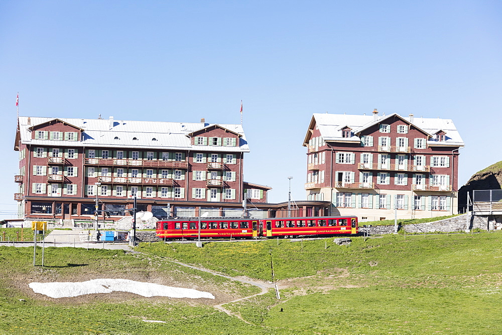 Red wagons of Wengernalpbahn rack railway run next to alpine hotels, Wengen, Bernese Oberland, Canton of Bern, Switzerland, Europe