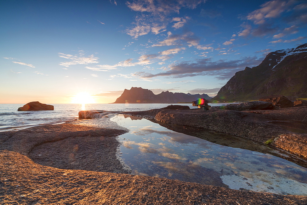 Pink clouds and midnight sun are reflected in the blue sea framed by rocky peaks, Uttakleiv, Lofoten Islands, Norway, Scandinavia, Europe