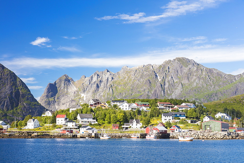 The blue sea frames the fishing village and the rocky peaks, Reine, Moskenesoya, Lofoten Islands, Norway, Scandinavia, Europe