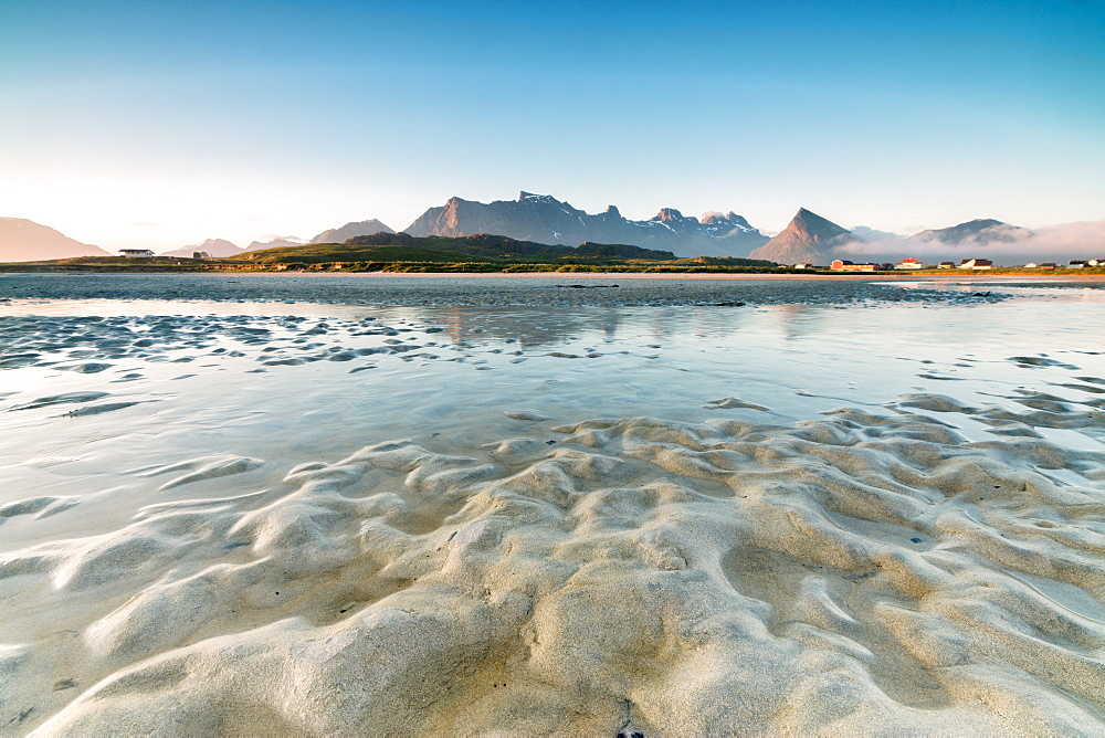 High peaks and midnight sun are reflected in the cold sea, Fredvang, Moskenesoya, Nordland county, Lofoten Islands, Norway, Scandinavia, Europe