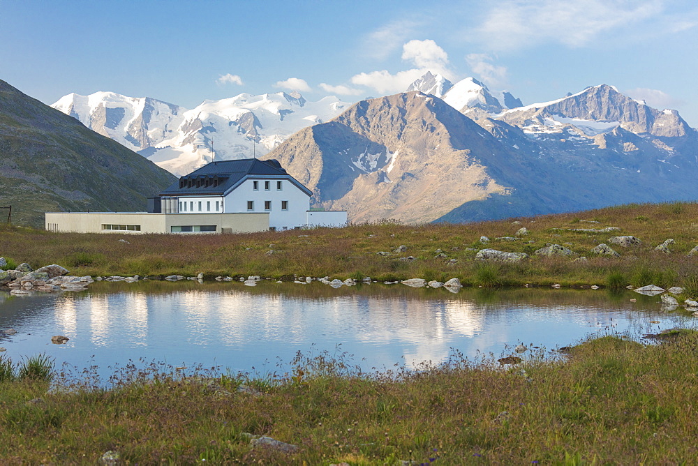 The alpine lake frames the hotel surrounded by peaks, Muottas Muragl, Samedan, Canton of Graubunden, Engadine, Switzerland, Europe