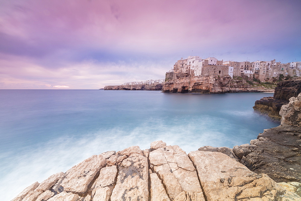 Pink sunrise on the turquoise sea framed by old town perched on the rocks, Polignano a Mare, Province of Bari, Apulia, Italy, Europe