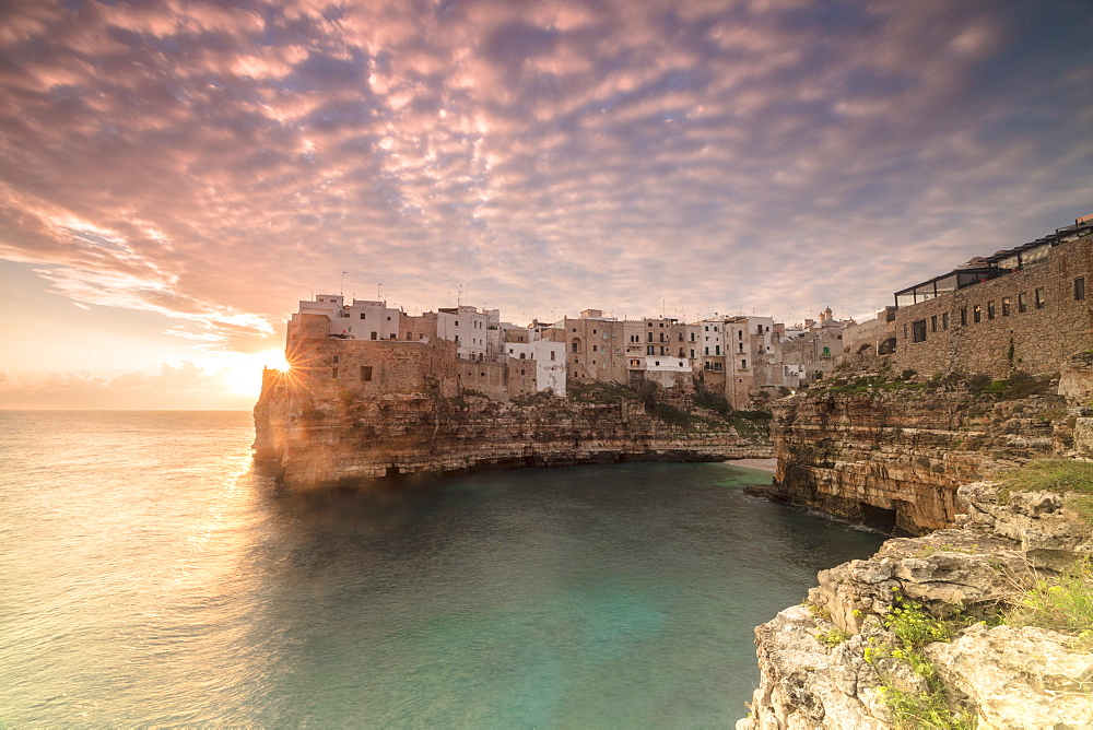 Pink sunrise on the turquoise sea framed by old town perched on the rocks, Polignano a Mare, Province of Bari, Apulia, Italy, Europe