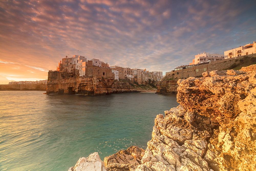 Pink sunrise on the turquoise sea framed by old town perched on the rocks, Polignano a Mare, Province of Bari, Apulia, Italy, Europe