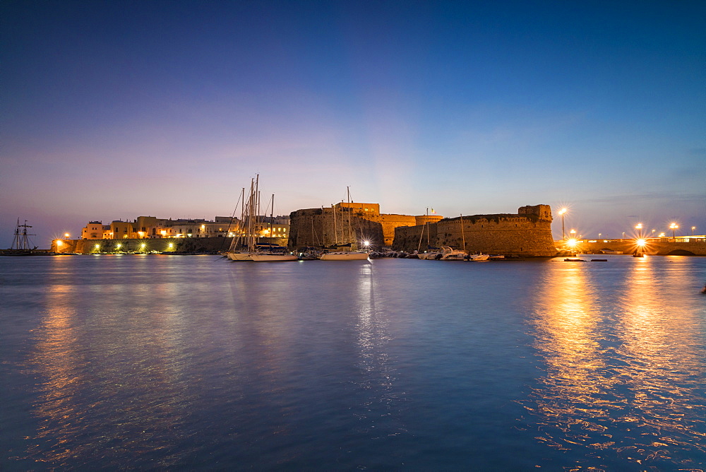 Dusk lights the harbor and the medieval old town of Gallipoli, Province of Lecce, Apulia, Italy, Europe